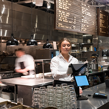 Woman working in busy kitchen of restaurant